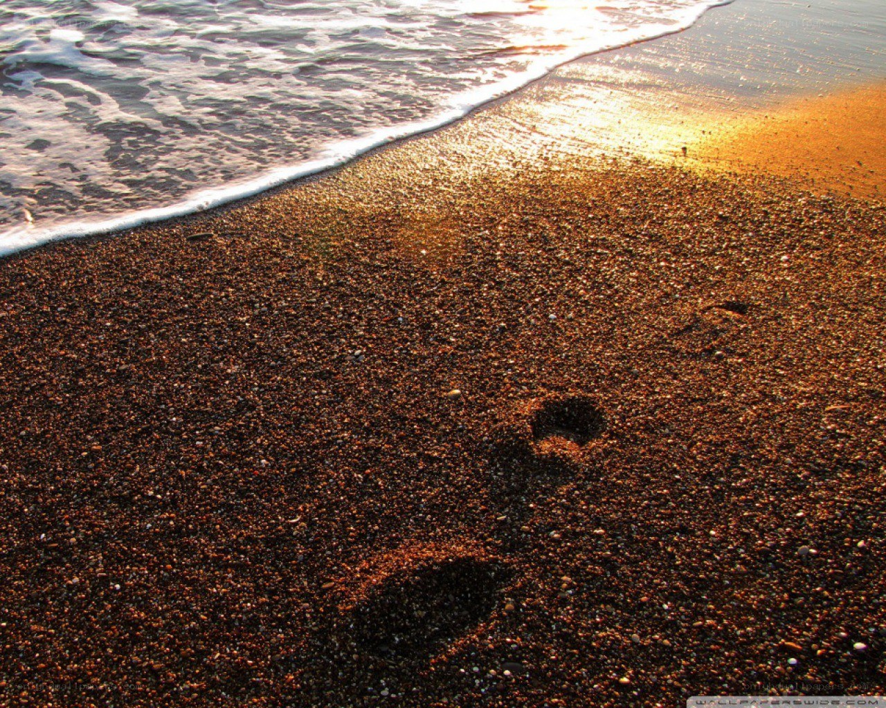 Footprints on a beach at sunset