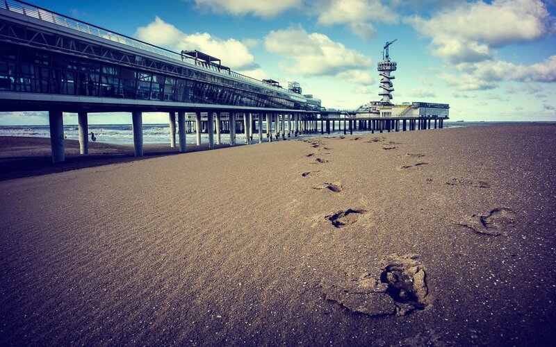 Footprints on a beach near a pier