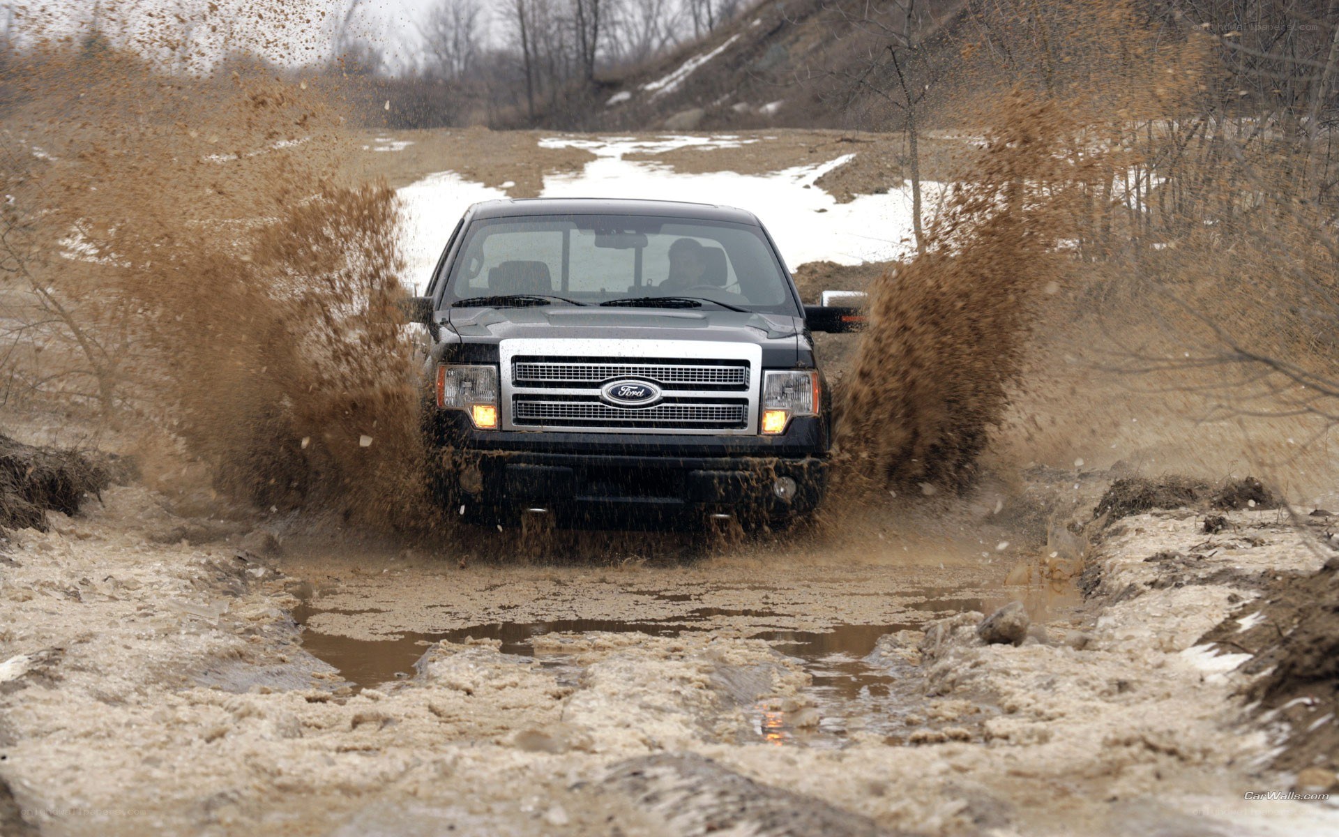 Ford truck driving through mud