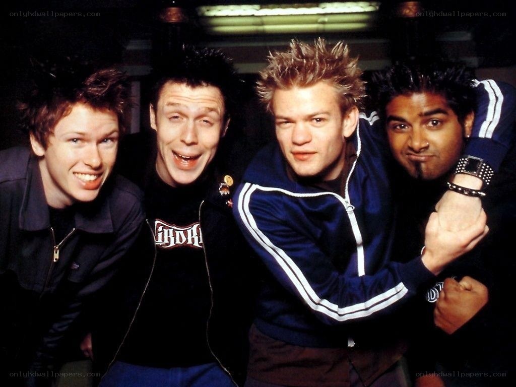 Four band members posing together