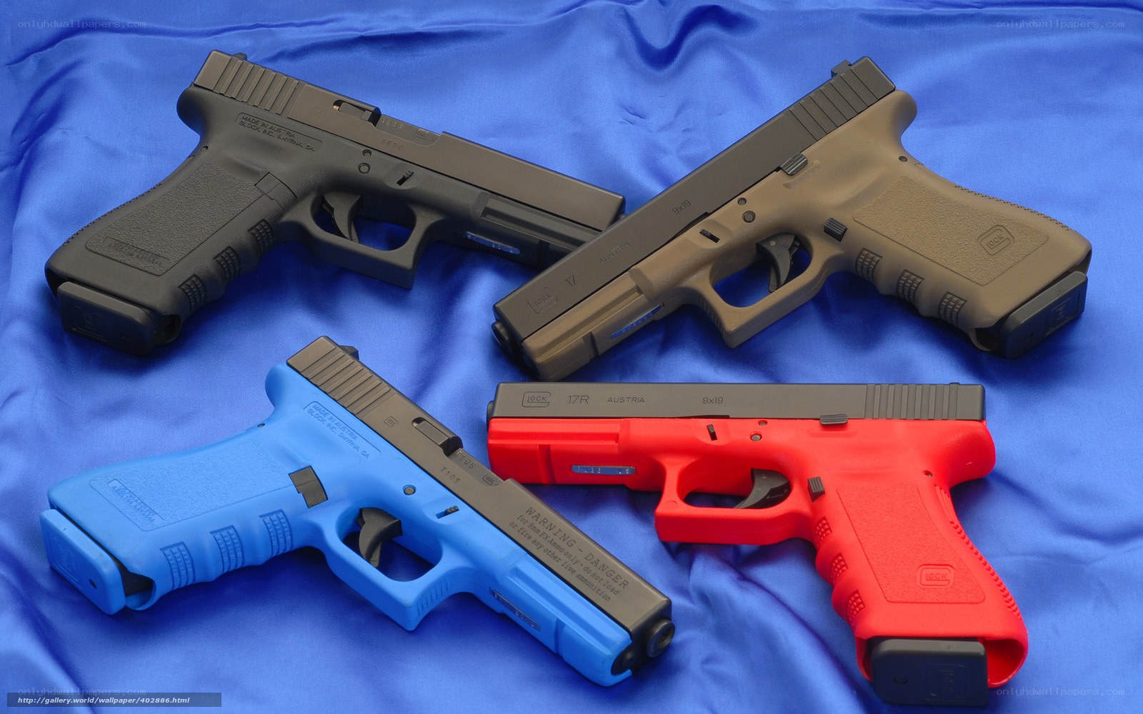 Four colored handguns on blue cloth