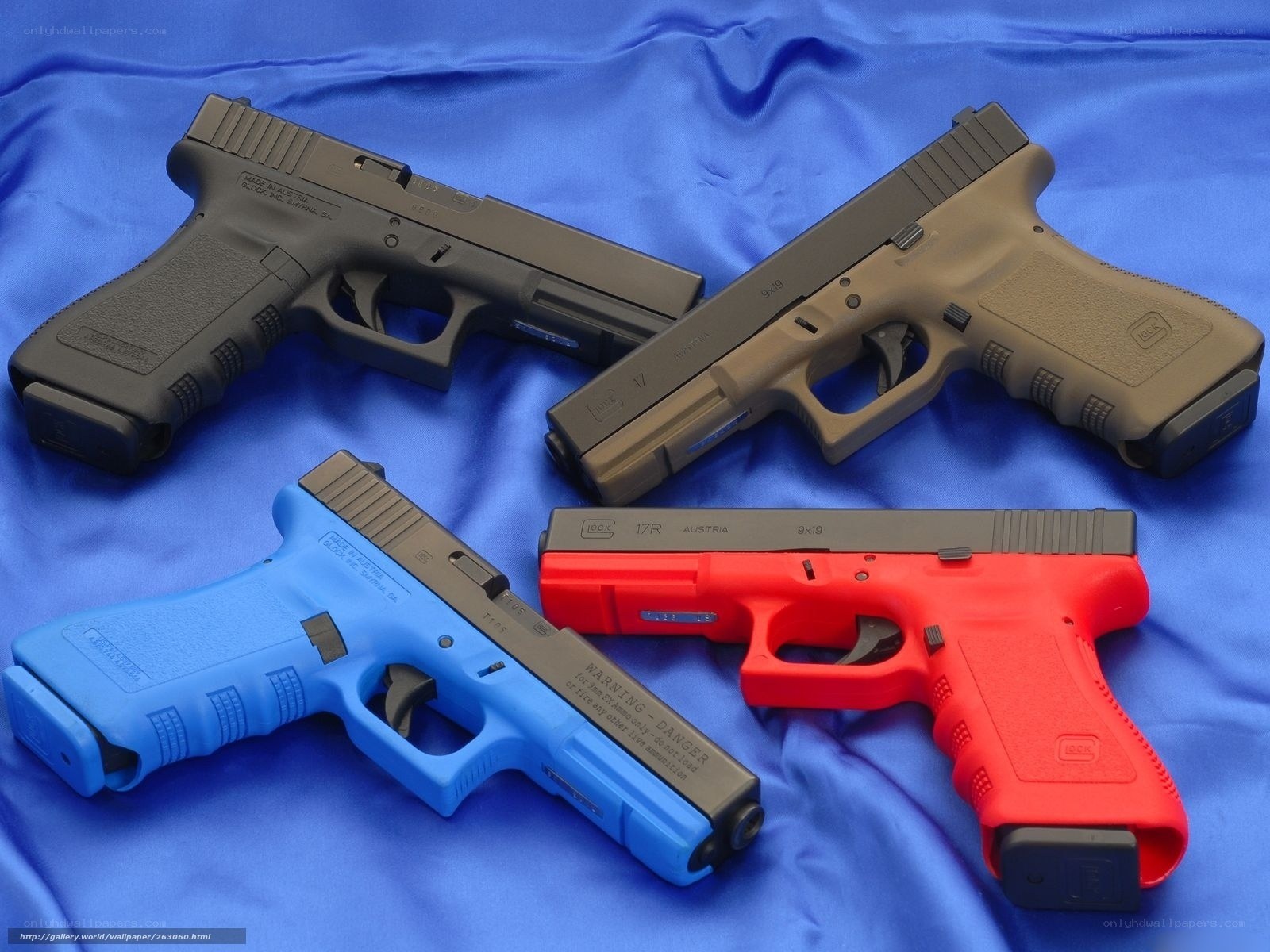 Four colored handguns on blue cloth