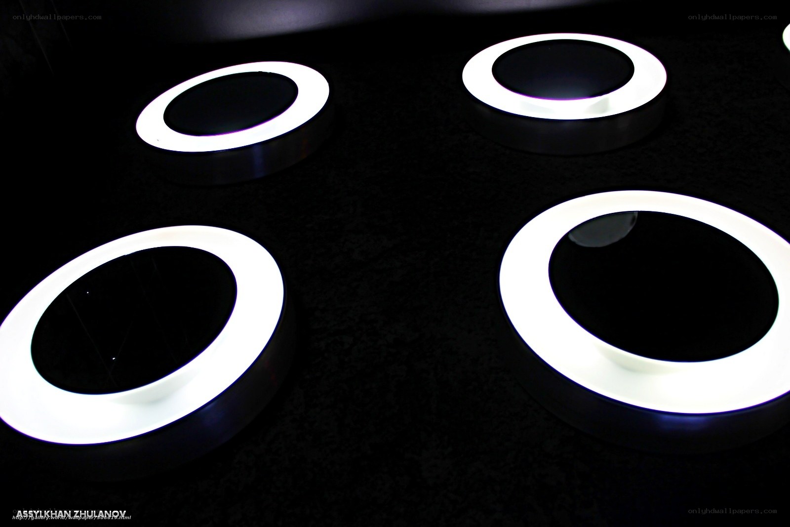 Four glowing rings on dark surface