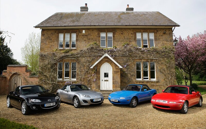 Four Mazda Miata cars in front of a house