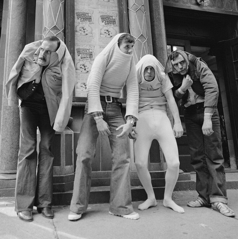 Four men in costumes on a street