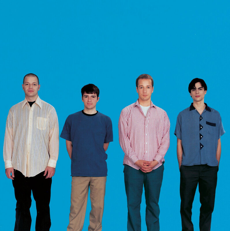 four men in front of blue background