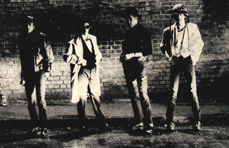 four men in front of brick wall