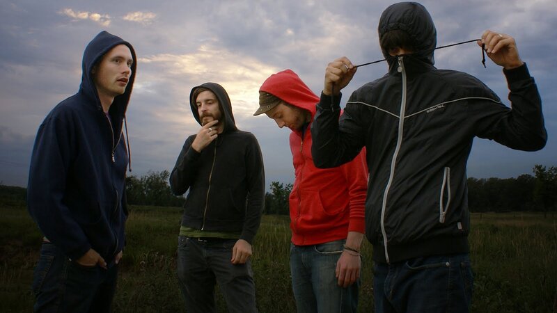four men in hoodies in a field