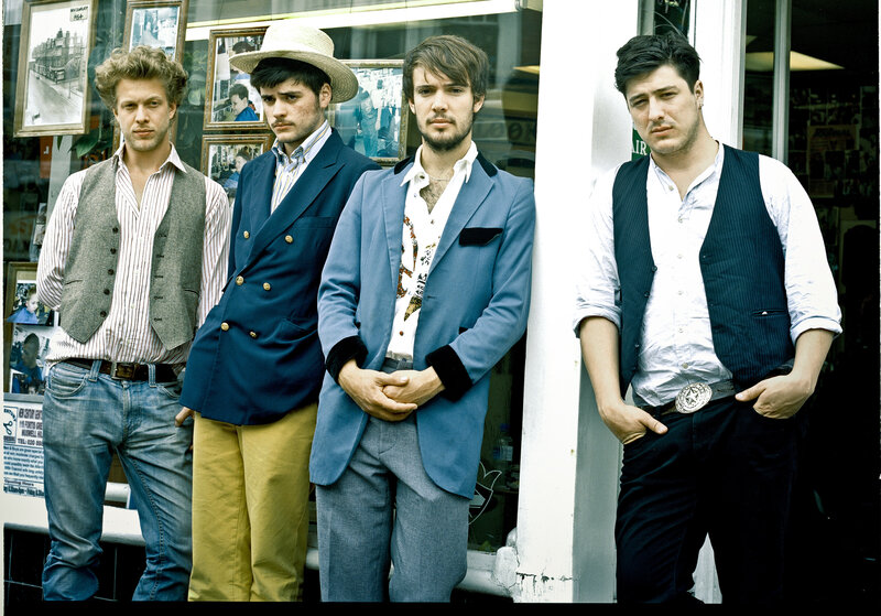Four men in stylish vests and blazers
