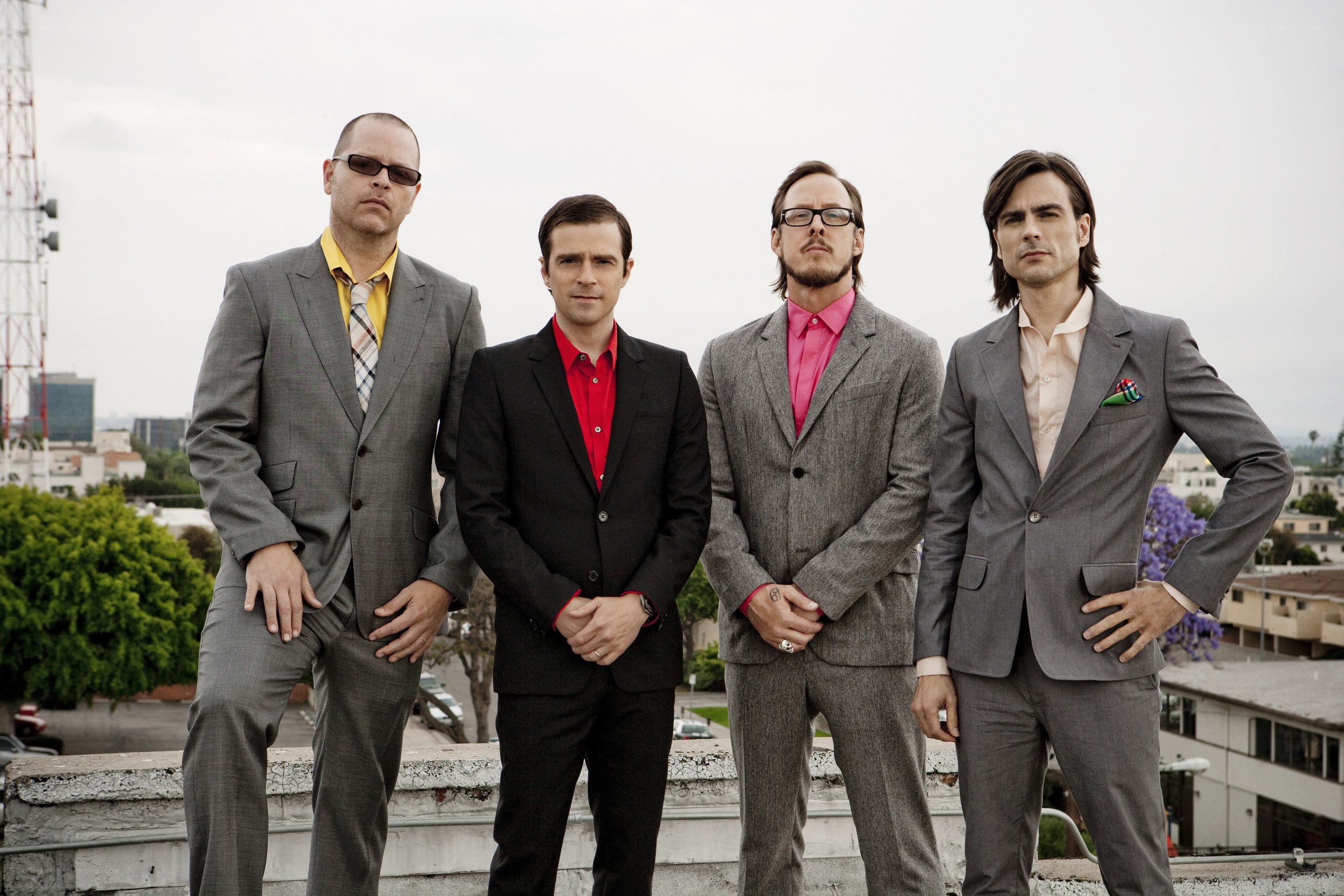 four men in suits on a rooftop