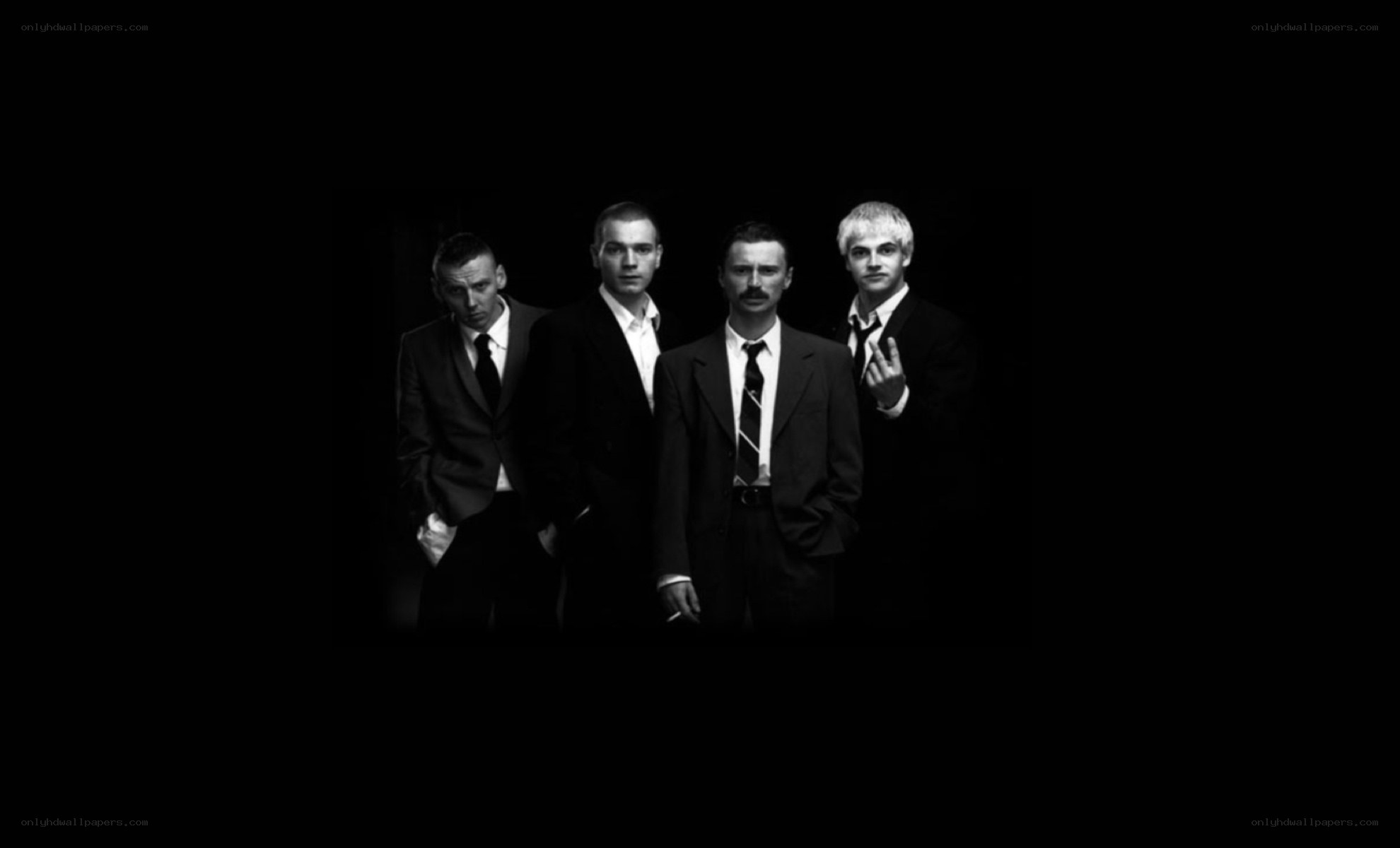 four men in suits on black background