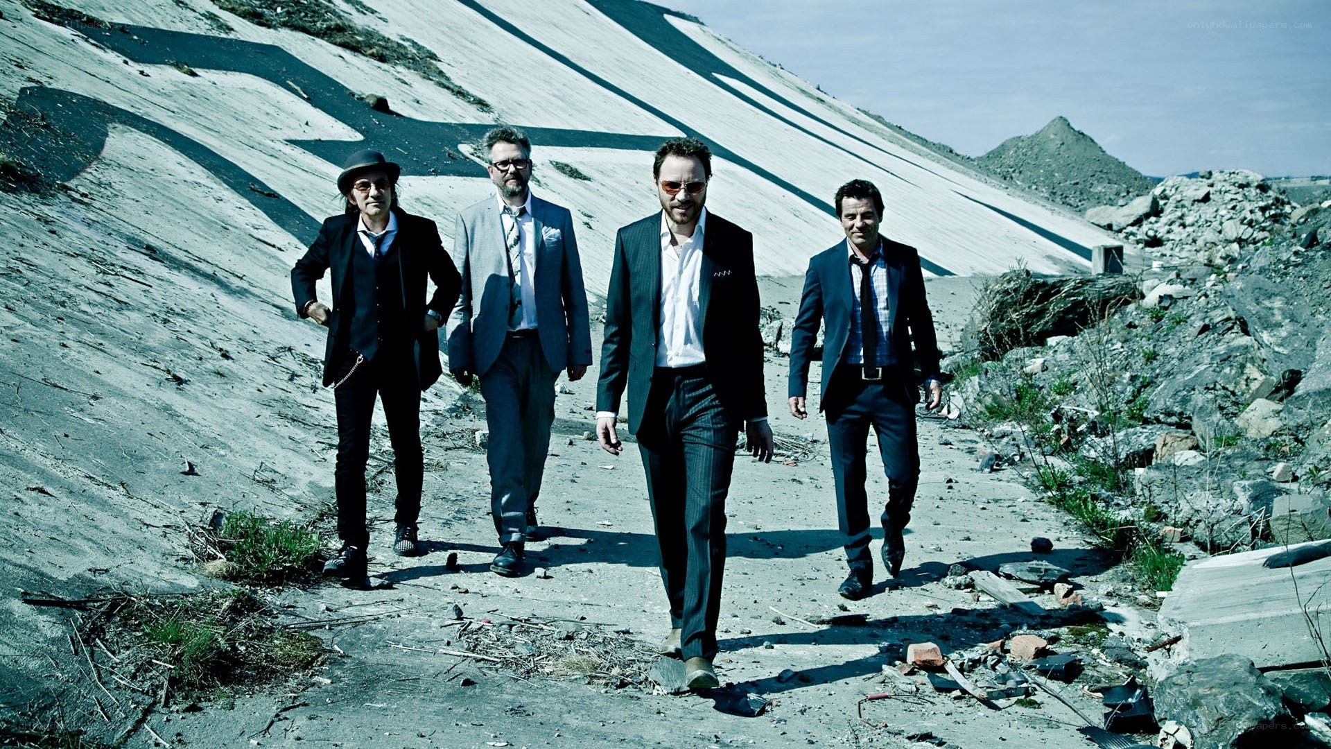 Four men in suits walking in a quarry