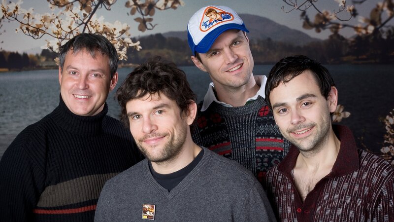 Four men posing by a lake