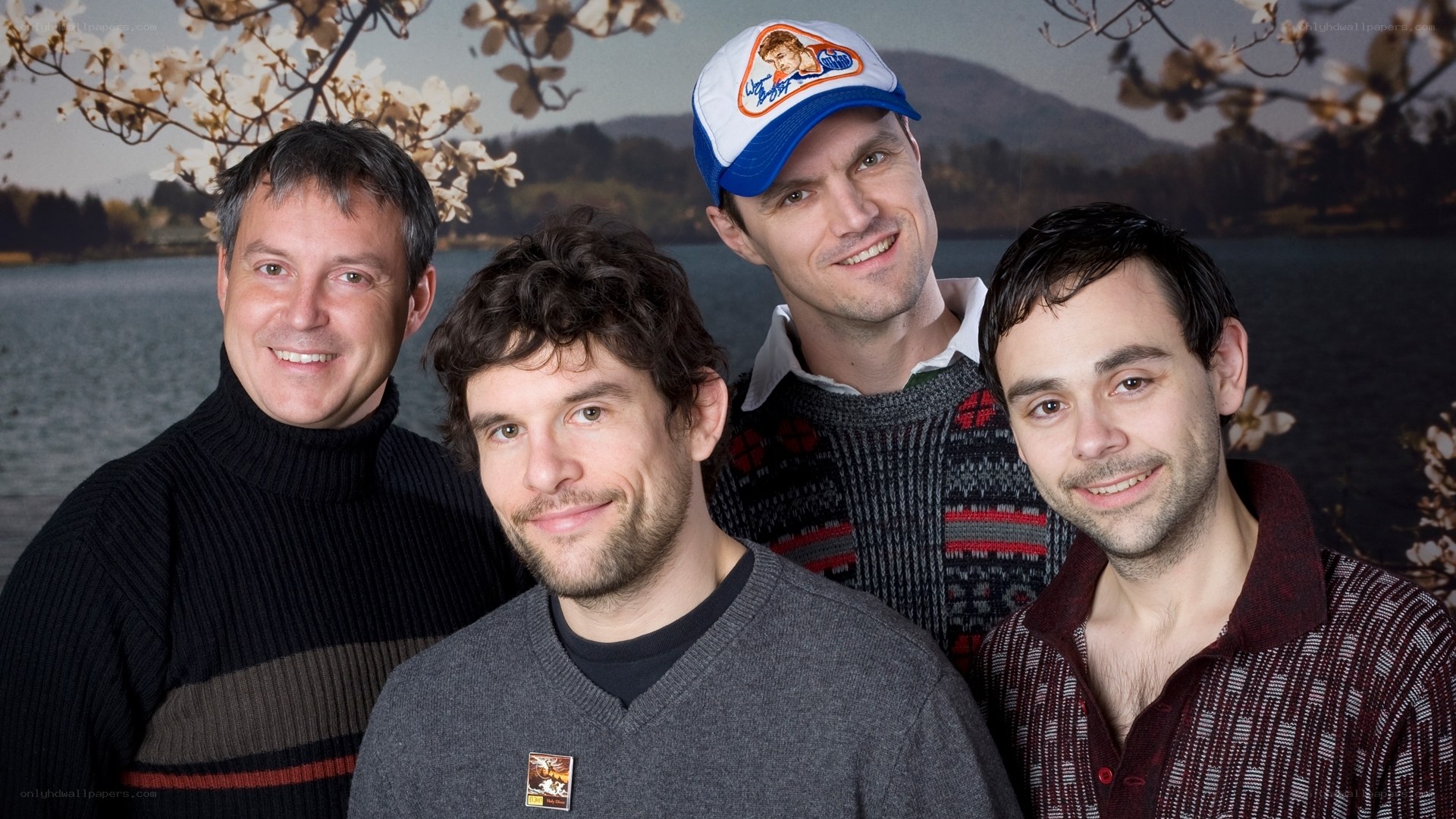 Four men posing by a lake