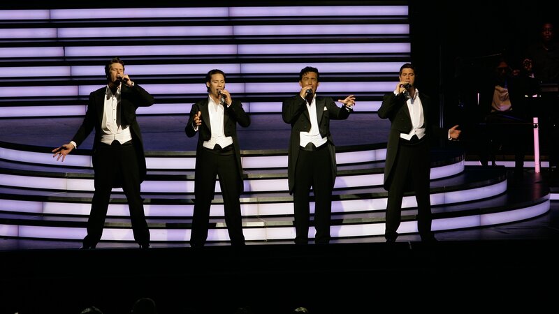 Four men singing on stage