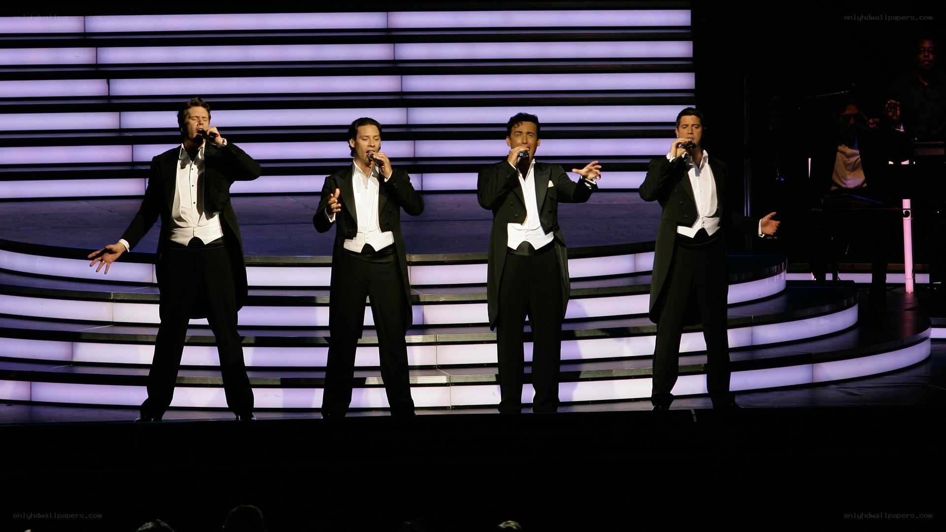Four men singing on stage