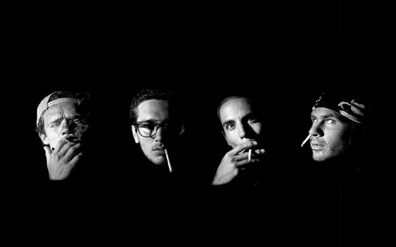four men smoking in black and white