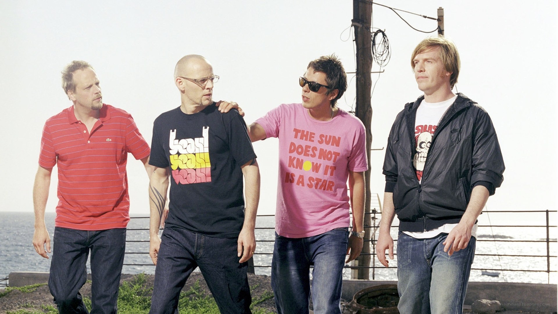 Four men standing by the sea