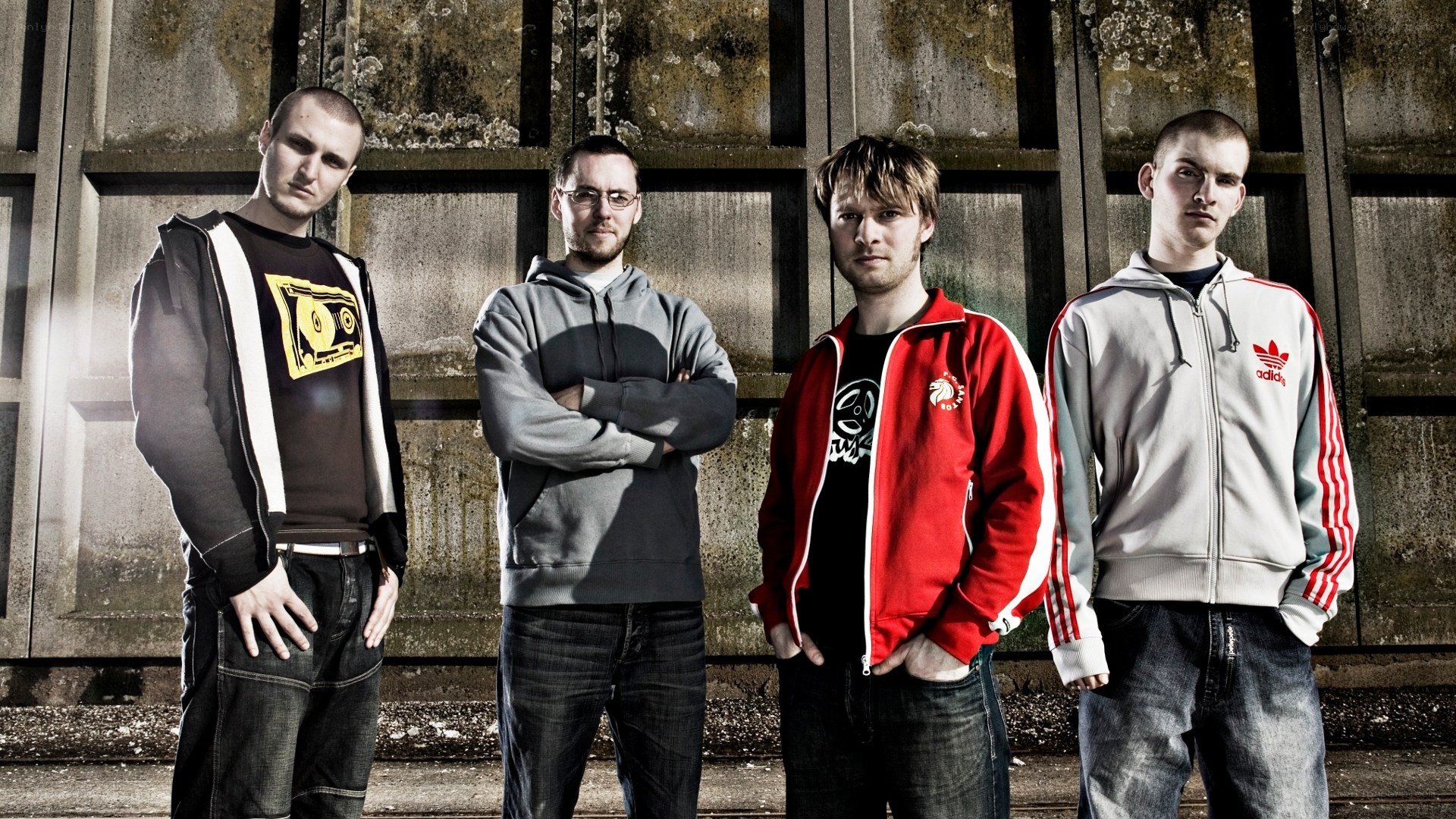four men standing in front of a wall