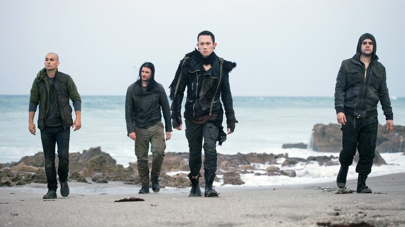 four men walking on beach
