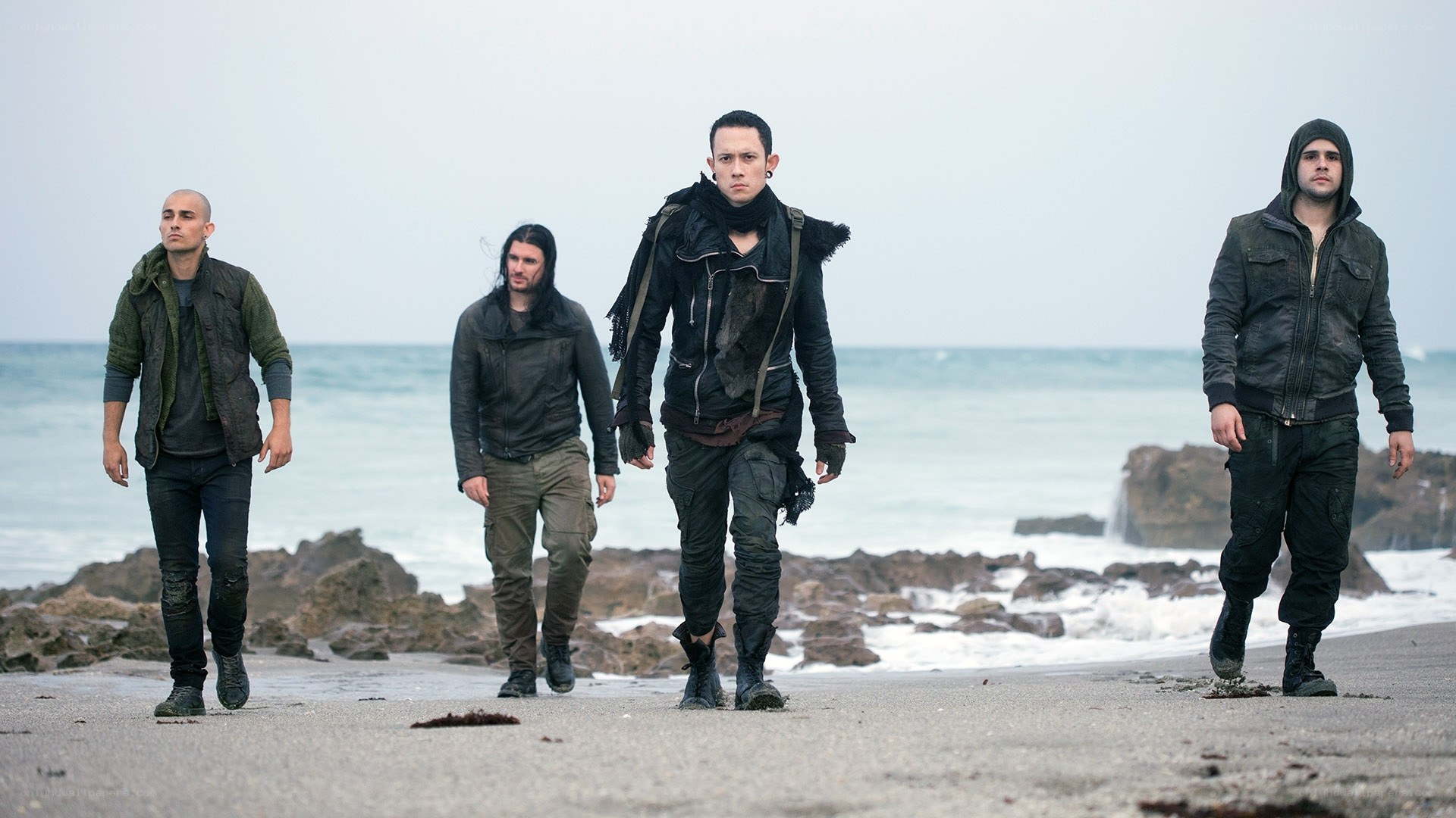four men walking on beach