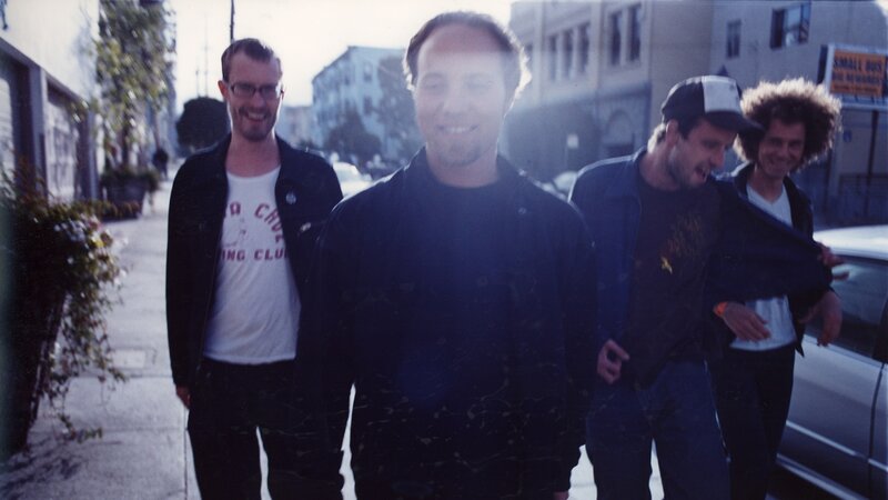 Four Men Walking on Sidewalk
