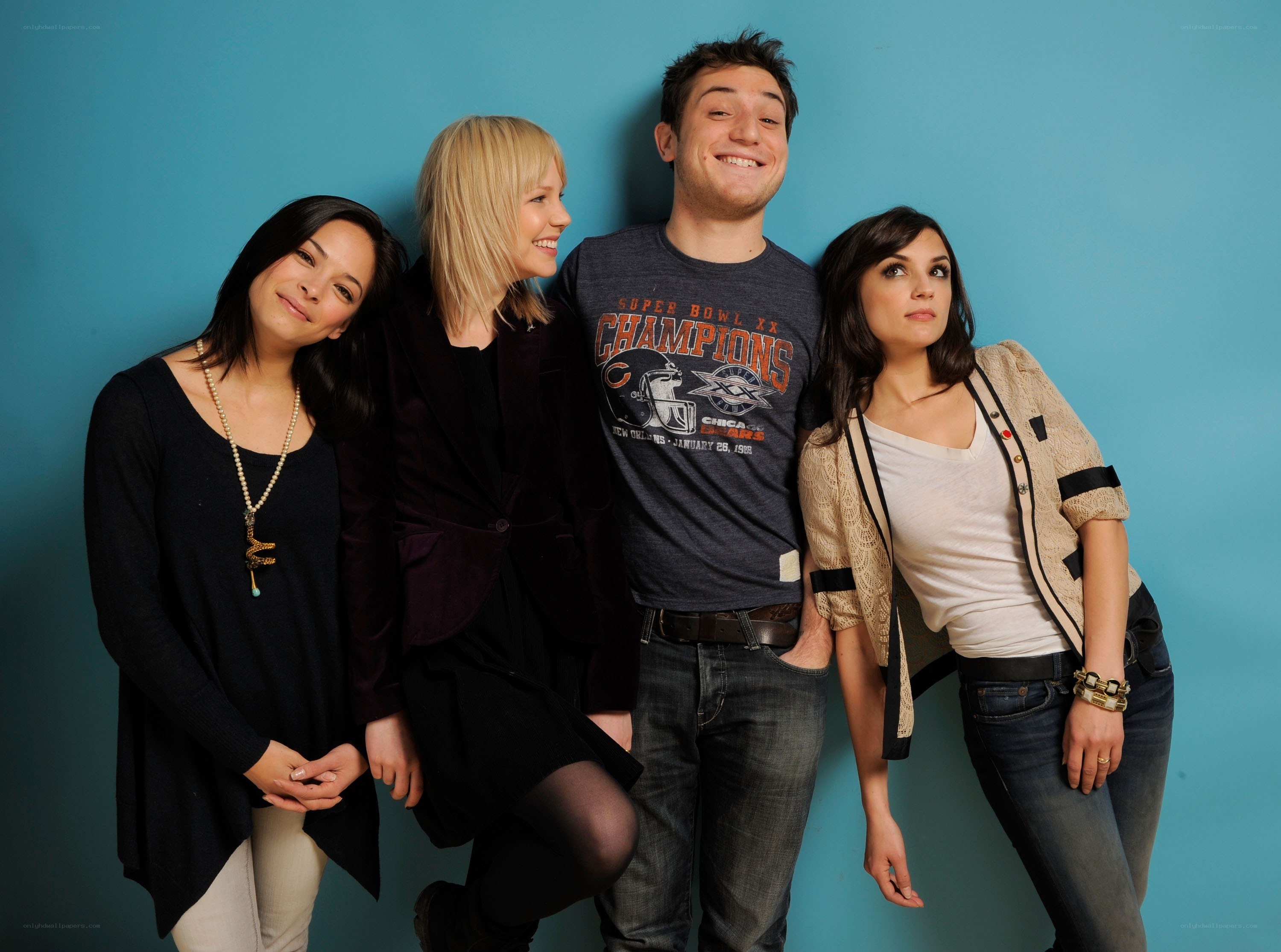 four people posing against blue wall