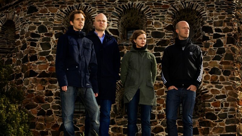 four people standing in front of stone wall