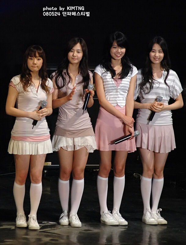four women on stage with microphones