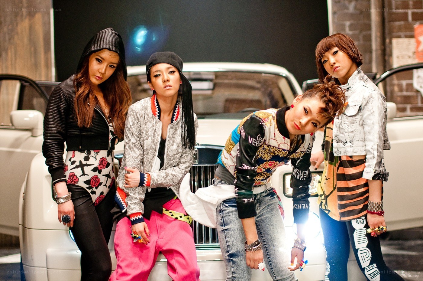 four women posing by a car