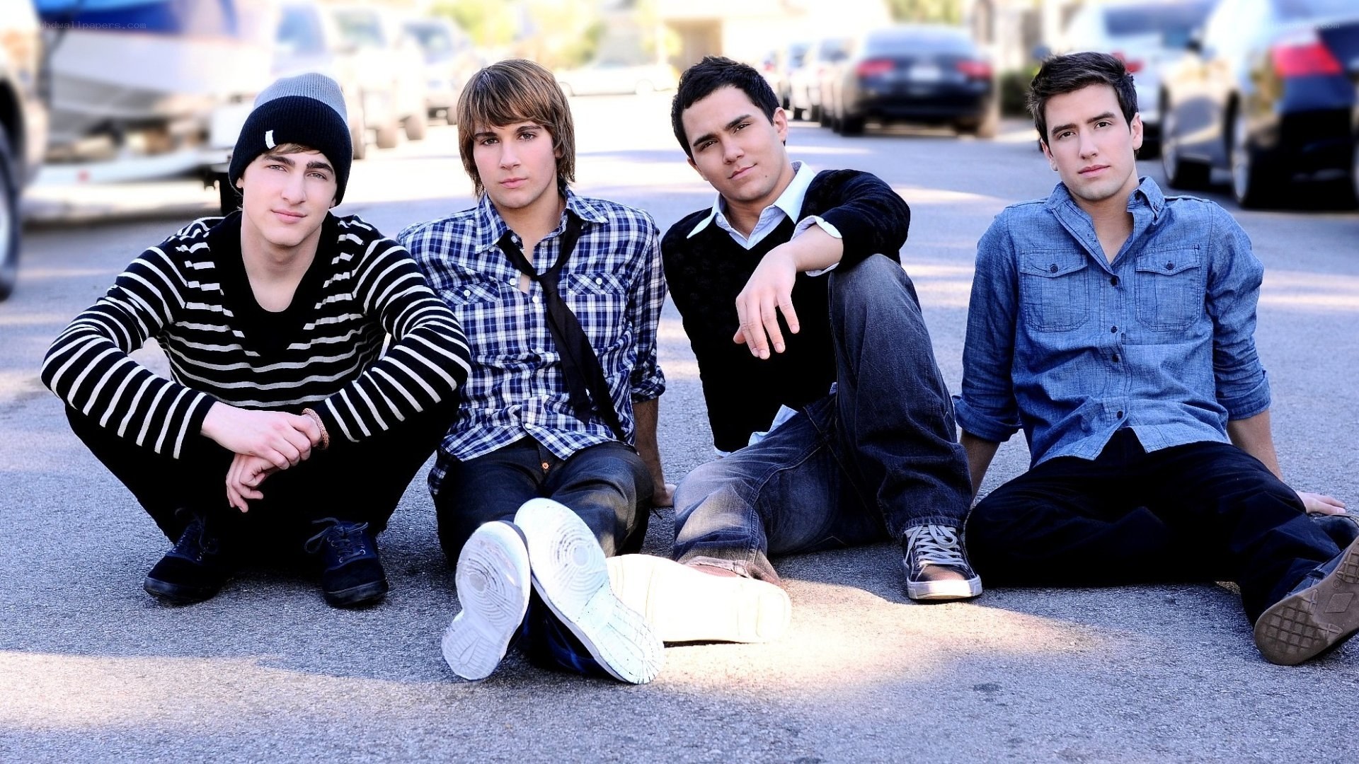 four young men sitting on pavement