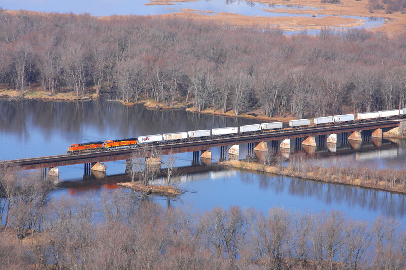 Freight train crossing river bridge