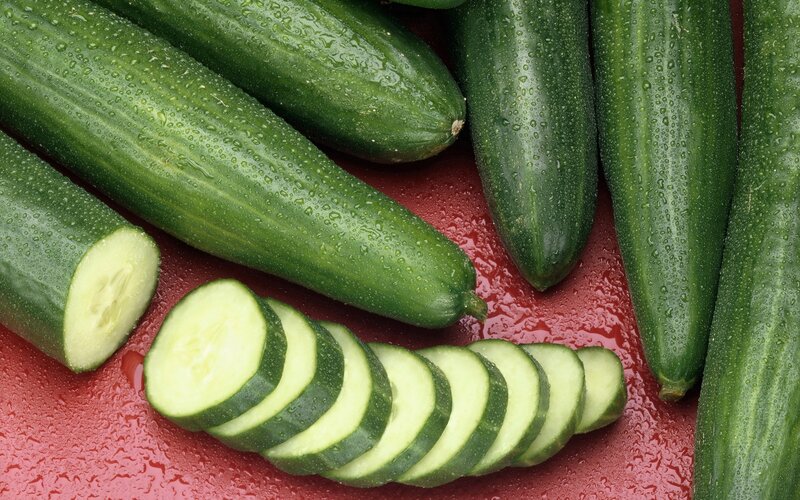 Fresh cucumbers on red surface