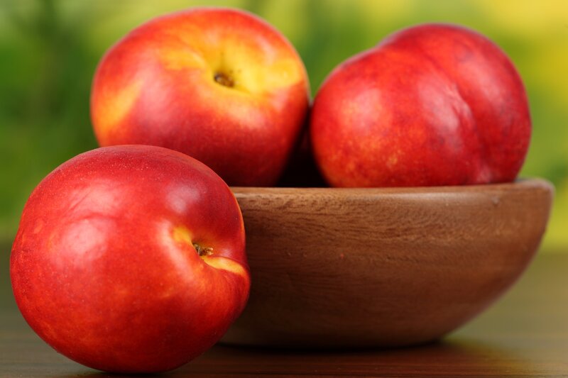 Fresh nectarines in a wooden bowl