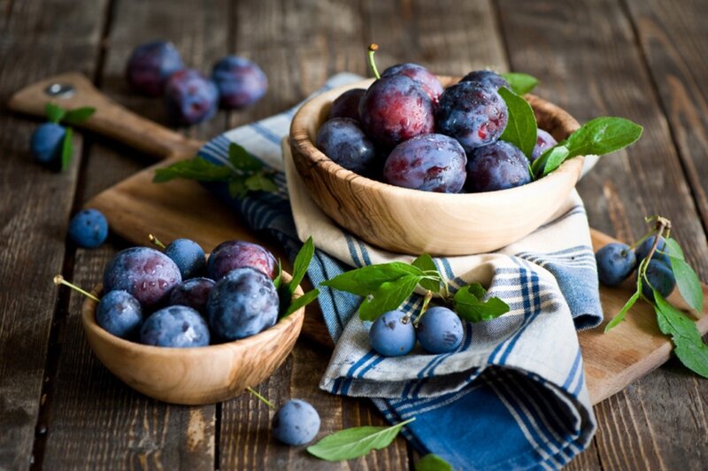 Fresh plums in wooden bowls