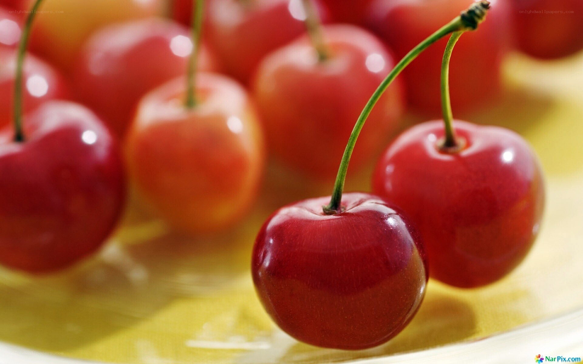 Fresh red cherries on a yellow surface