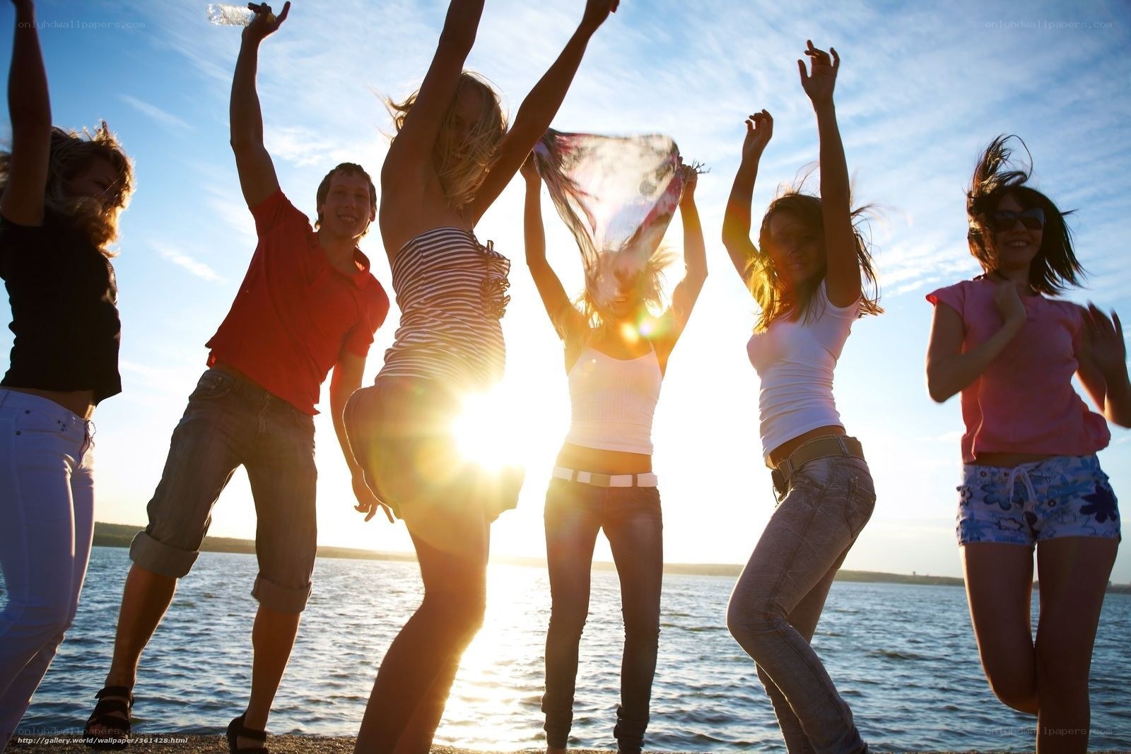 Friends dancing at sunset by the water
