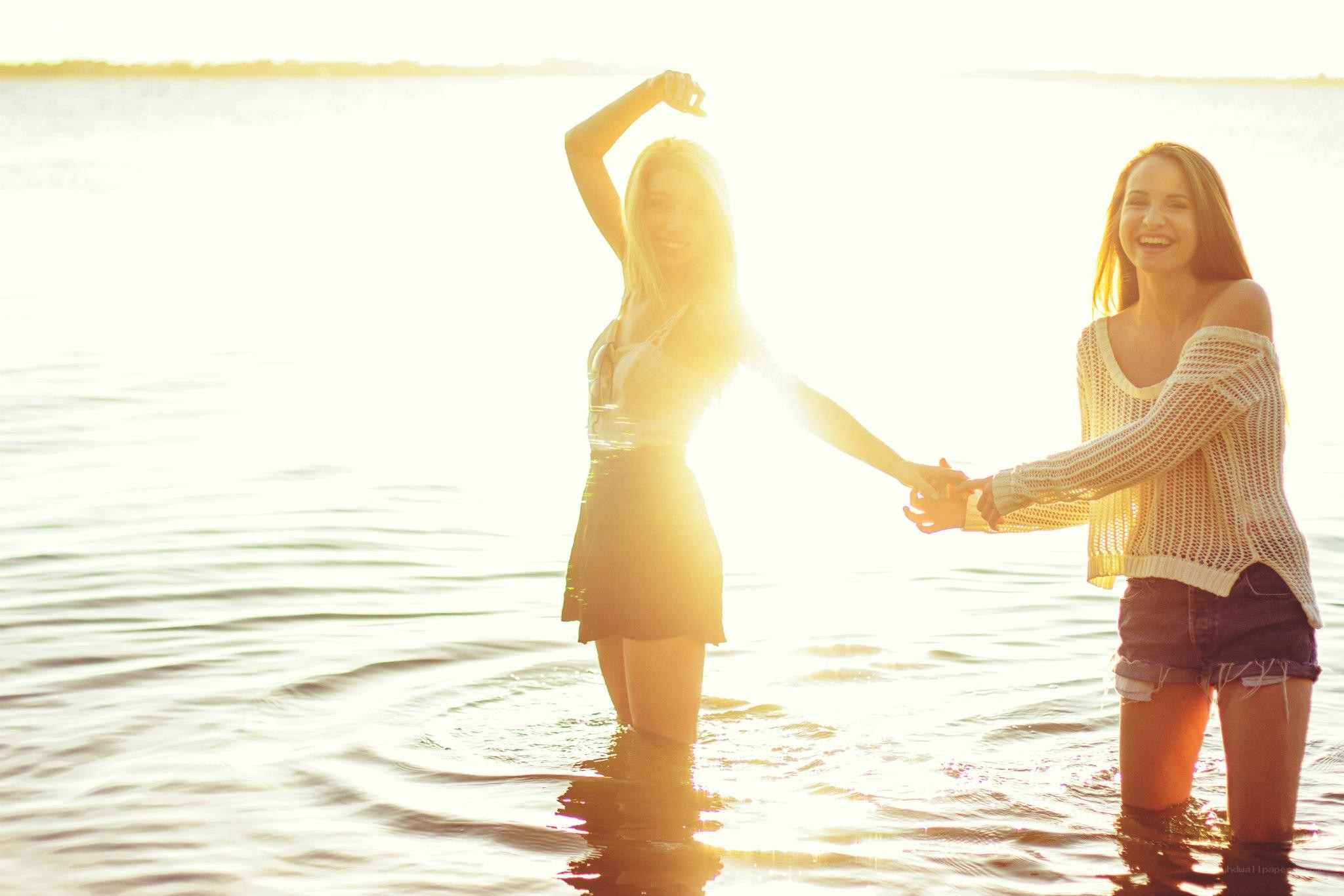 Friends holding hands in water