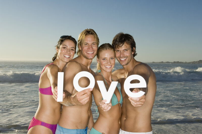 Friends holding 'love' on beach
