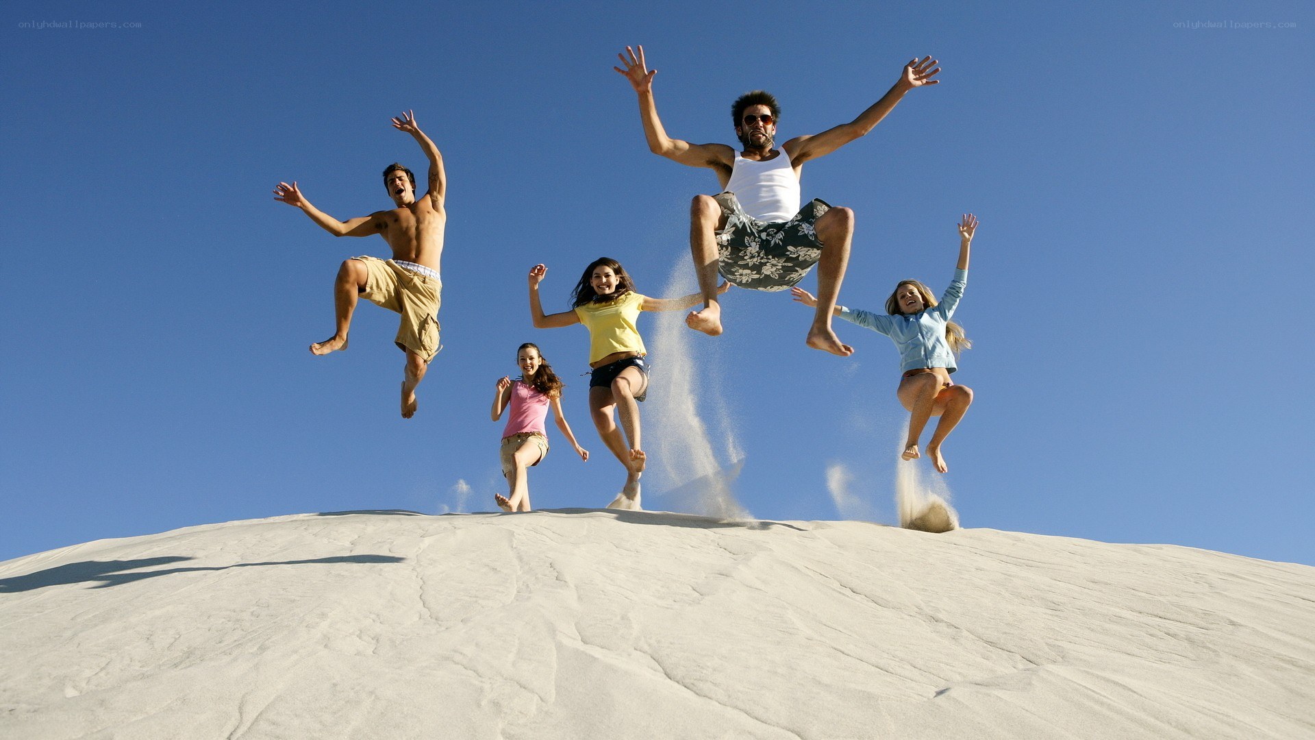 Friends jumping on a sand dune