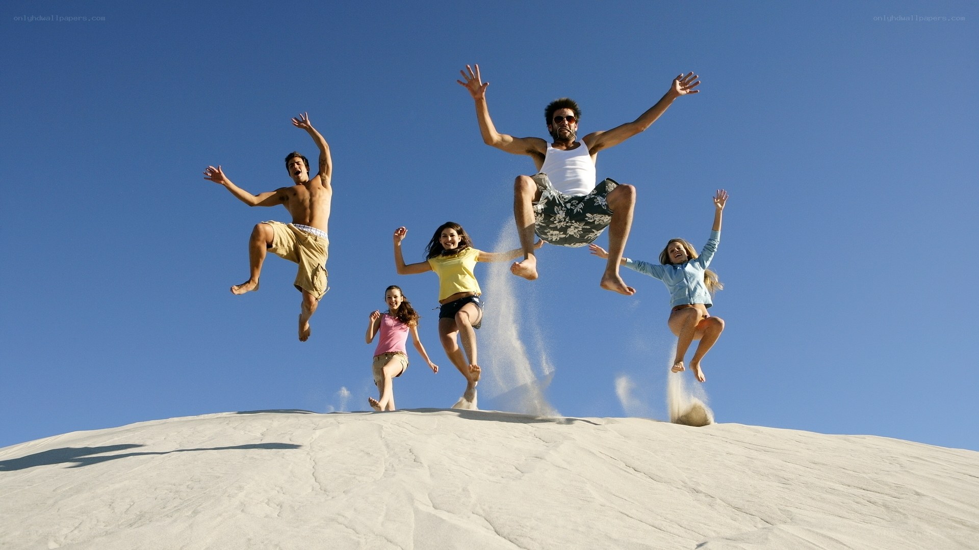 Friends jumping on sand dune