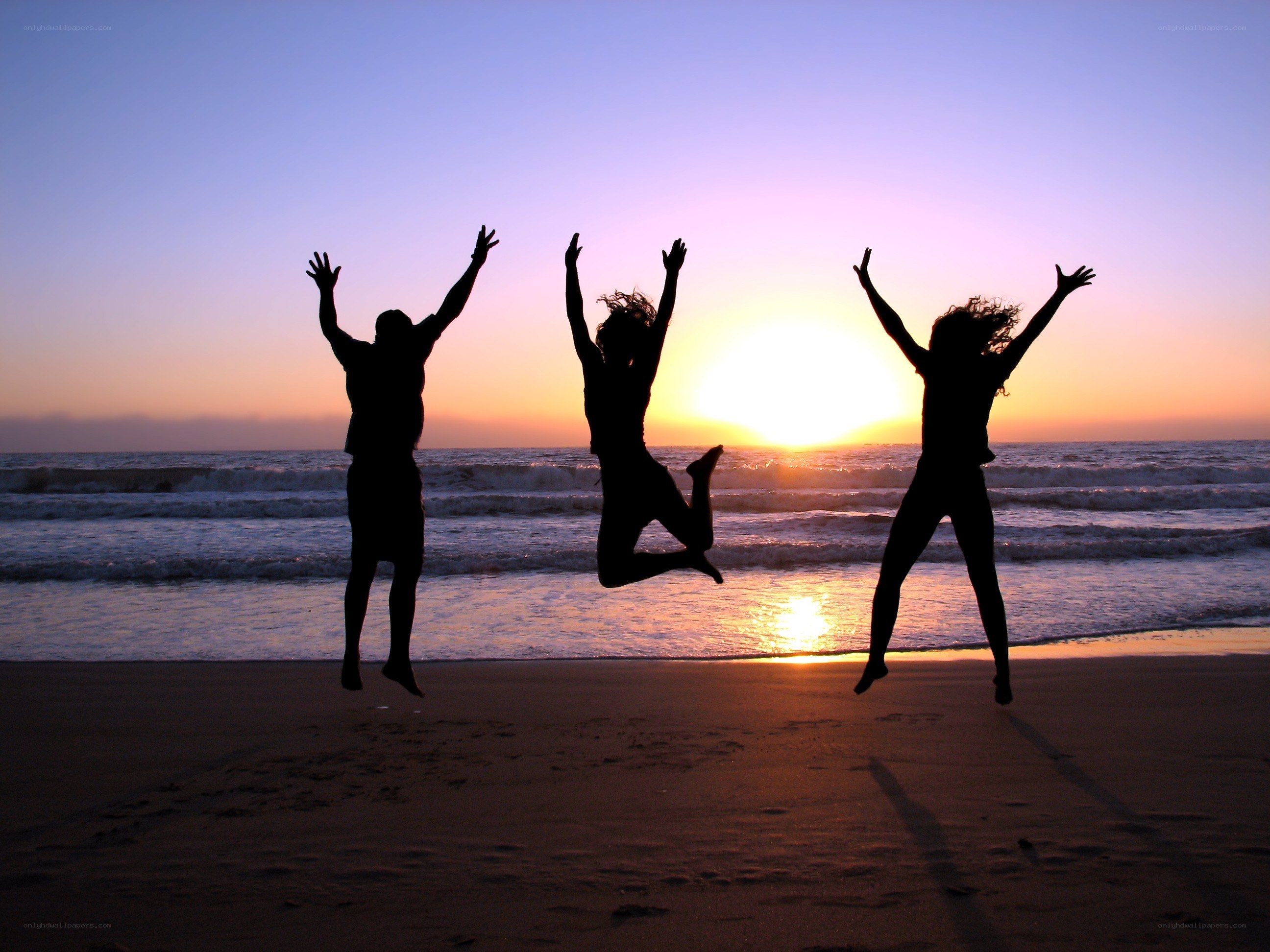 Friends jumping on the beach at sunset