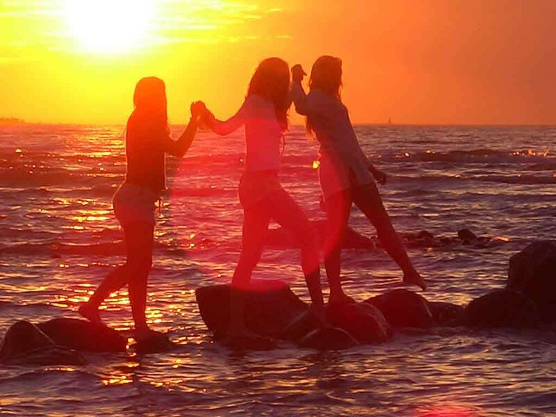 Friends on rocks at sunset