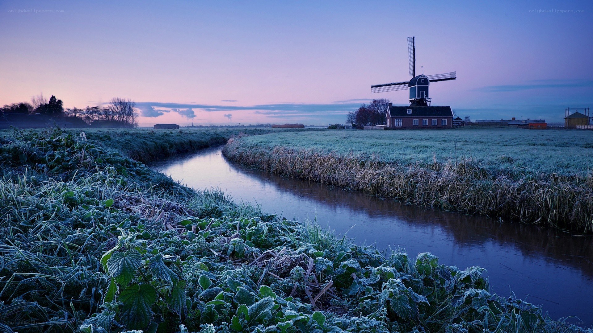Frosty canal with windmill at dawn