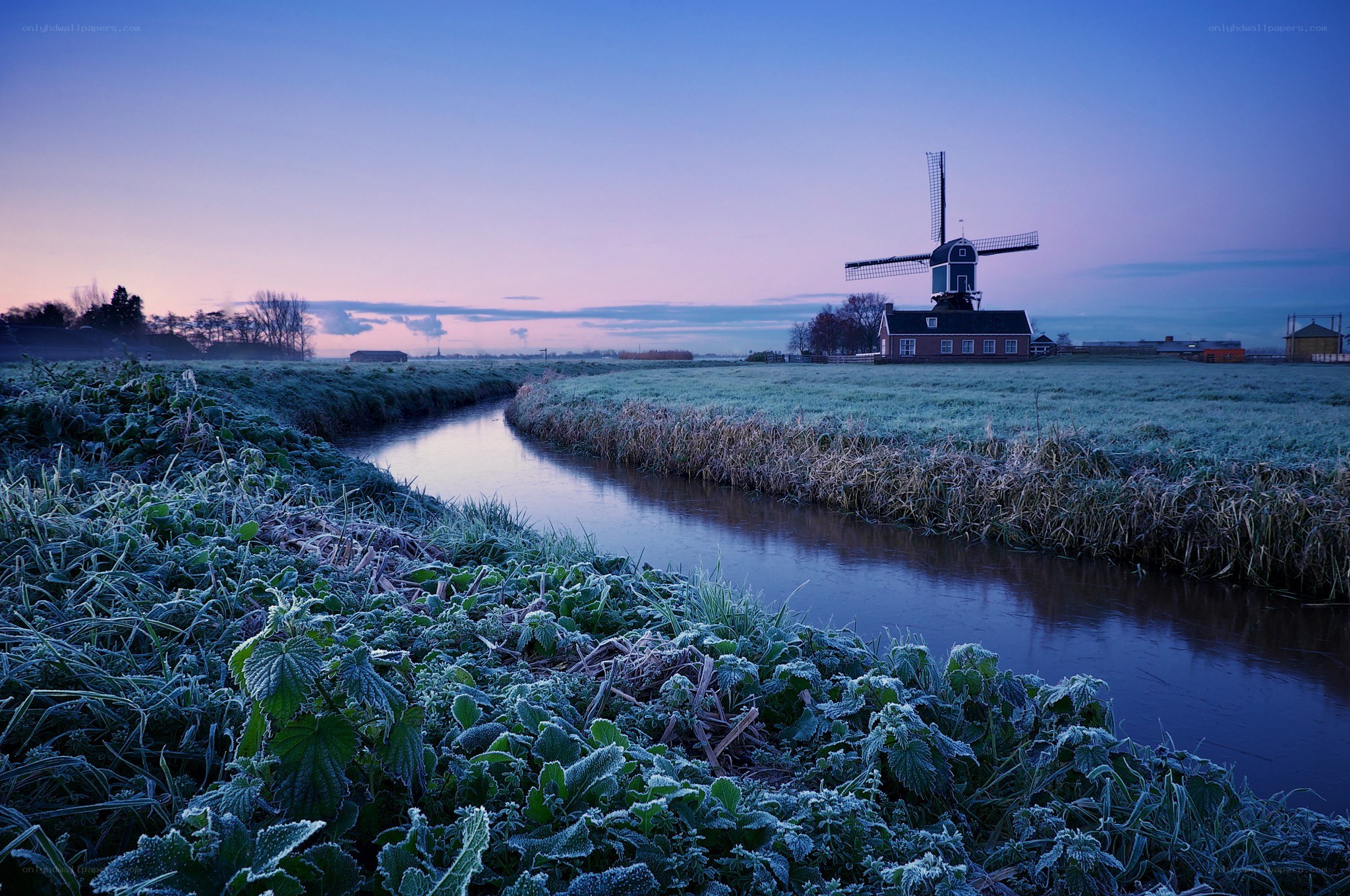 Frosty canal with windmill at dawn