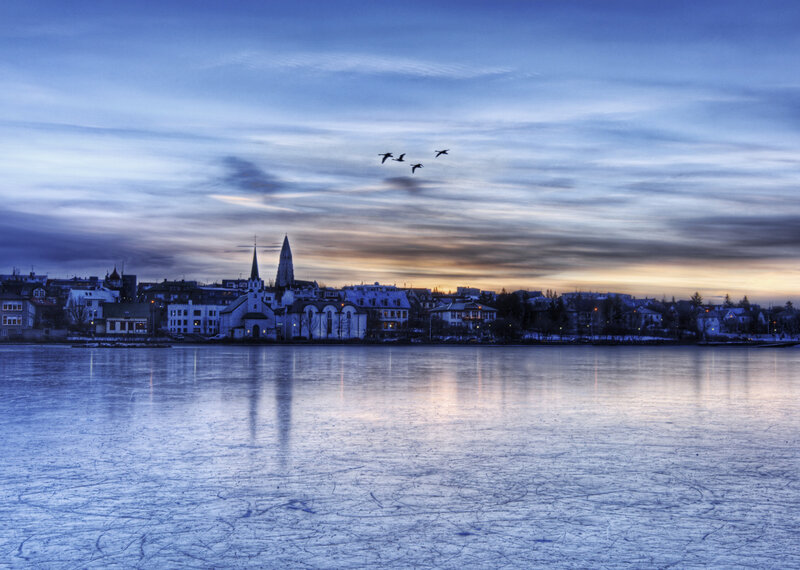 Frozen lake at dusk with city skyline