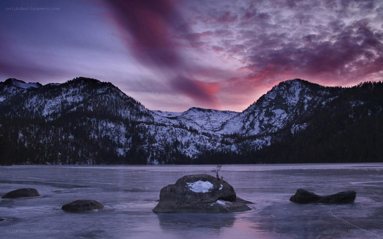 Frozen lake at sunset with mountains