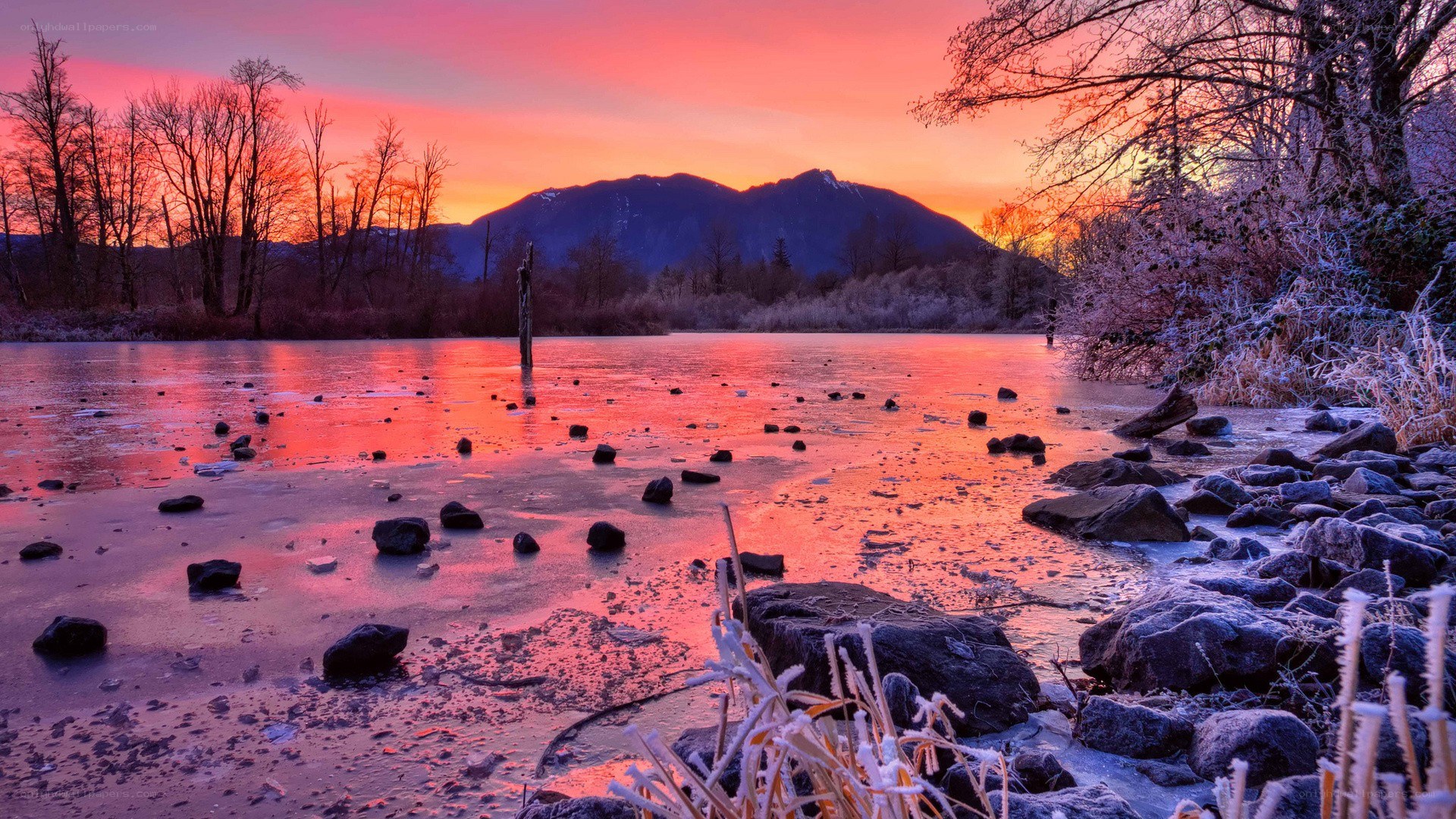 Frozen lake at sunset with mountains
