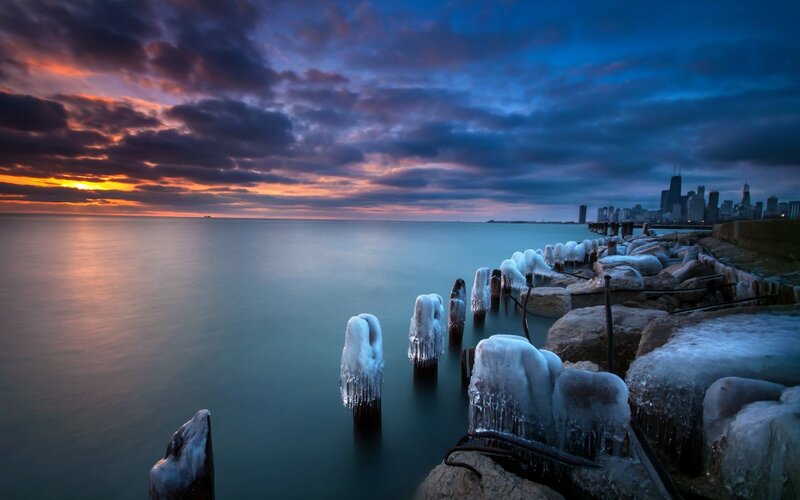 Frozen pier at sunset with city skyline