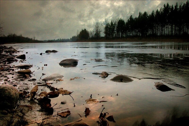 Frozen river with rocks and trees